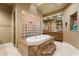 Bright bathroom featuring a large tub with marble surround and glass block accent wall at 6626 E Oberlin Way, Scottsdale, AZ 85266