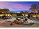 Backyard pool with lounge chairs, manicured shrubbery, rock waterfall, and a beautiful sunset sky at 6626 E Oberlin Way, Scottsdale, AZ 85266