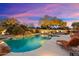 Lounge by a sparkling pool with a rock waterfall and desert plants, enhanced by landscape lighting at 6626 E Oberlin Way, Scottsdale, AZ 85266