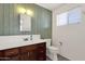 The bathroom features a sleek mirror, a white counter with a dark wood cabinet, and green wood paneling at 6934 E Coronado Rd, Scottsdale, AZ 85257