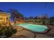 Inviting backyard pool featuring stone accents, desert landscaping, and an umbrella-covered patio. The perfect spot for relaxation at 7149 E Quartz St, Mesa, AZ 85207