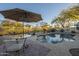 Inviting kidney-shaped pool featuring a table with umbrella, surrounded by desert landscaping and privacy fencing at 7149 E Quartz St, Mesa, AZ 85207