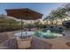 Backyard pool with an umbrella-covered table, desert landscaping, and a private setting for outdoor enjoyment at 7149 E Quartz St, Mesa, AZ 85207