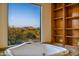 Bathroom featuring a soaking tub with scenic outdoor views and custom shelving at 7500 E Roy Rogers Rd, Scottsdale, AZ 85266