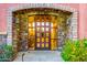 An arched, stone entryway leads to a beautiful wooden and glass front door at 7500 E Roy Rogers Rd, Scottsdale, AZ 85266