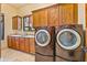 Convenient laundry room with front load washer, dryer and wood cabinets at 7500 E Roy Rogers Rd, Scottsdale, AZ 85266