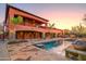 Stunning rear exterior with pool, spa, waterfall feature, and outdoor dining area at sunset at 7500 E Roy Rogers Rd, Scottsdale, AZ 85266