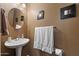 Stylish half bathroom features pedestal sink, decorative framed wall art, and neutral color scheme at 77 W Diamond Trl, San Tan Valley, AZ 85143