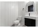 Modern powder room featuring wood-look floors, white plank walls, and sleek black and white vanity with arched mirror at 781 W Flintlock Way, Chandler, AZ 85286