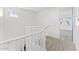 Upstairs hallway boasts neutral carpet, white railing, and bright natural light filtering in through a window and doorway at 781 W Flintlock Way, Chandler, AZ 85286