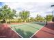 A tennis court with a green surface, surrounded by a black fence and mature desert landscaping under a blue sky at 8634 E Kael Cir, Mesa, AZ 85207