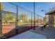 A fenced tennis court area with green and red surface, a shaded rest area with a bench, and desert landscaping at 8634 E Kael Cir, Mesa, AZ 85207