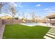 A backyard with a pool, artificial turf, and a covered patio provides space for outdoor relaxation and entertainment at 9144 W Quail Ave, Peoria, AZ 85382