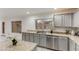 Kitchen with stone counters, gray cabinets, stainless dishwasher and double sink under a bright window at 9144 W Quail Ave, Peoria, AZ 85382