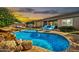 Beautiful pool and rock waterfall against the warm sunset, surrounded by landscaping and comfortable seating at 9388 W Cashman Dr, Peoria, AZ 85383