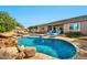 Lush backyard with a sparkling pool, rock waterfall, tanning ledge, comfortable seating, and mature landscaping at 9388 W Cashman Dr, Peoria, AZ 85383