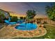 Gorgeous backyard pool with a rock waterfall and slide, surrounded by lush landscaping and lounge chairs at 9388 W Cashman Dr, Peoria, AZ 85383