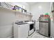 Well-lit laundry room with modern washer, dryer, ample shelving, and a mini fridge, for convenience at 9388 W Cashman Dr, Peoria, AZ 85383