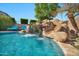 Gorgeous pool featuring a rock waterfall and slide, surrounded by lush landscaping and comfortable lounge chairs at 9388 W Cashman Dr, Peoria, AZ 85383