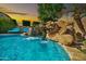 Gorgeous pool featuring a rock waterfall and slide, surrounded by lush landscaping and comfortable lounge chairs at 9388 W Cashman Dr, Peoria, AZ 85383