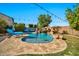 Gorgeous backyard pool with a rock waterfall and slide, surrounded by lush landscaping and lounge chairs at 9388 W Cashman Dr, Peoria, AZ 85383
