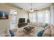 Staged living room with furniture, a TV, and a view into the kitchen and hallway at 10622 W Mohawk Ln, Peoria, AZ 85382