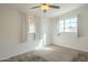 Light filled bedroom featuring a ceiling fan and two windows with sun drenched carpeted floors at 11305 W Alabama Ave, Youngtown, AZ 85363