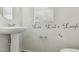 Cozy half bath with pedestal sink, decorative wall art, and neutral tones at 12054 W Aster W Dr, El Mirage, AZ 85335