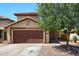 Charming two-story home featuring a brown garage door, desert landscaping, and a welcoming front entrance at 12054 W Aster W Dr, El Mirage, AZ 85335