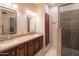 Bathroom featuring a double sink vanity with granite countertops and a glass-enclosed shower at 13913 W Whitewood Dr, Sun City West, AZ 85375