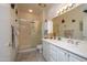 Well-lit bathroom with white cabinets, double sinks, shower, and decorative butterflies on the walls at 15770 W Remington Dr, Surprise, AZ 85374