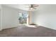 A spacious bedroom with carpet flooring, a ceiling fan, and access to the balcony at 18239 N 40Th St # 107, Phoenix, AZ 85032