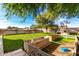 Spacious backyard featuring lush lawn, playset, wooden planter boxes, and mature trees at 19412 W Clarendon Ave, Litchfield Park, AZ 85340