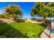 Large grassy backyard with mature trees, wooden planter boxes, and playset features at 19412 W Clarendon Ave, Litchfield Park, AZ 85340