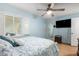 Bright bedroom featuring a ceiling fan, plantation shutters, light blue walls, and a wall-mounted television at 19412 W Clarendon Ave, Litchfield Park, AZ 85340