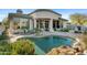 A backyard swimming pool with rock features, surrounded by lush landscaping and a covered patio at 6426 N 27Th St, Phoenix, AZ 85016