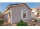 Side view of the house with neutral stucco, white trim, and landscaped rock ground covering at 665 E Winchester Way, Chandler, AZ 85286