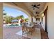 Charming covered patio with dining area, ceiling fans, tv, and view of the refreshing pool and lush landscaping at 6960 E Ivyglen St, Mesa, AZ 85207