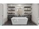 Luxurious bathroom with a soaking tub, dark tile accent wall, and sleek floating shelves at 7528 E 1St St, Scottsdale, AZ 85251