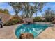 Inviting pool area with travertine tile, natural rock features, and mature shade trees creating a relaxing backyard oasis at 7740 E Gainey Ranch Rd # 36, Scottsdale, AZ 85258