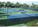 Well-maintained tennis courts with a seating area, enclosed by fencing and surrounded by lush greenery at 7740 E Gainey Ranch Rd # 36, Scottsdale, AZ 85258