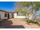 Paver patio with a mature tree with grass accents along a white stucco privacy wall and arched entryway at 9001 S 18Th Way, Phoenix, AZ 85042