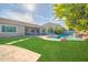 Spacious backyard featuring lush green lawn, sparkling pool with rock waterfall, and outdoor seating areas at 9388 W Cashman Dr, Peoria, AZ 85383