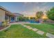 Expansive backyard with lush grass, a pool with waterfall, and a covered patio for outdoor enjoyment at 9388 W Cashman Dr, Peoria, AZ 85383