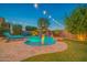 Resort style backyard pool with a rock waterfall and tanning deck, lounge seating and ambient lighting at 9388 W Cashman Dr, Peoria, AZ 85383