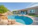Sparkling pool with rock features, sun loungers, and manicured landscaping create a backyard oasis at 9388 W Cashman Dr, Peoria, AZ 85383
