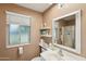 Bathroom with a large window, a sink, and large mirror, next to a standalone shower with clear glass door at 10303 W Desert Forest N Cir, Sun City, AZ 85351
