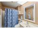 Bathroom featuring a shower and tub, toilet, sink, mirror, and blue decorative shower curtain at 10303 W Desert Forest N Cir, Sun City, AZ 85351