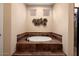 A soaking tub is enclosed by tile flooring and features two small windows and a decorative art piece at 12715 W Crestvale Dr, Peoria, AZ 85383