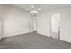 Neutral bedroom with carpet, a ceiling fan, and an arched entryway leading to the bathroom at 13408 W Mauna Loa Ln, Surprise, AZ 85379